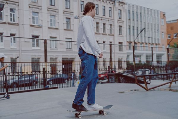 Skater in white long sleeve tee on skateboard, back view